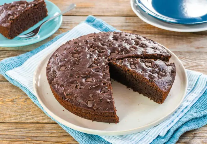 Deliziosa torta vegana al cioccolato, cosparsa di gocce e pezzi di cioccolato fondente, pronta per essere gustata.