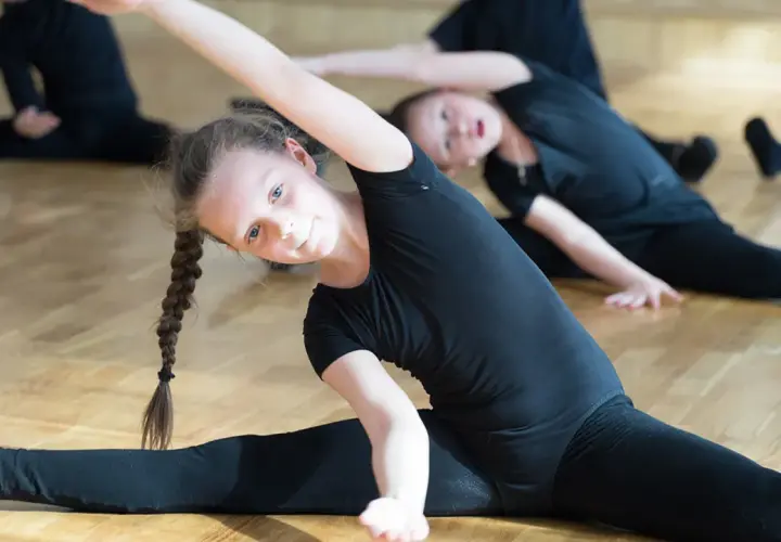 Niñas bailarinas estirando sus piernas en el suelo.