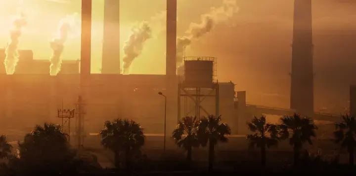 Paisaje industrial con chimeneas humeantes al atardecer. Ojalá se pudiera aplicar **limpieza con ozono** para purificar el aire.