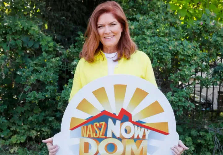 Katarzyna Dowbor z uśmiechem prezentuje tablicę z napisem "Nasz Nowy Dom".