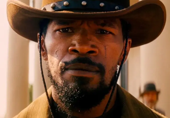 Primo piano di Jamie Foxx nei panni di Django, con cappello da cowboy e barba. Il suo sguardo intenso evoca il significato di libertà e vendetta in Django Unchained.