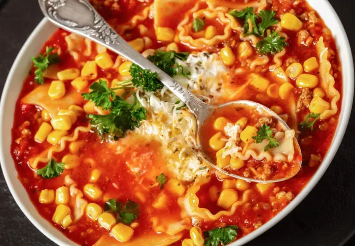 Herzhafte Lasagne Suppe mit Mais, Hackfleisch und Nudeln, garniert mit Petersilie und Käse. Eine Löffelprobe zeigt die köstlichen Zutaten.
