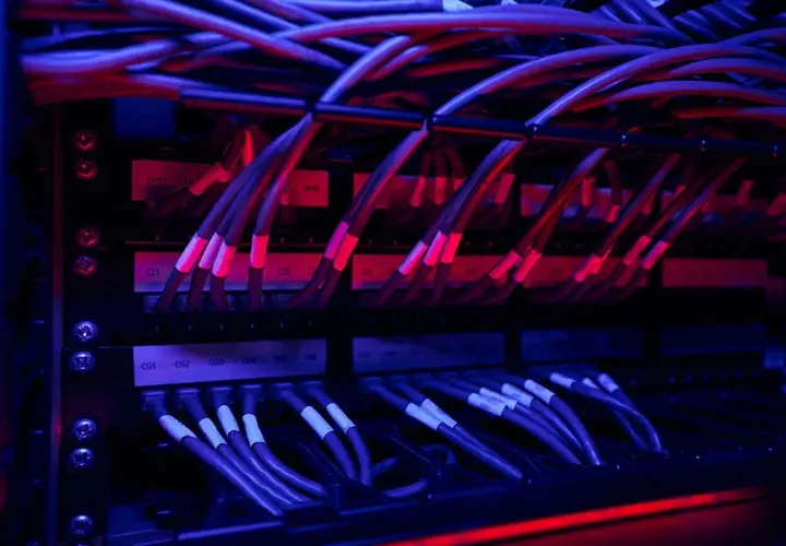 Red y azul iluminan un rack de servidores con un intrincado **cableado horizontal**.