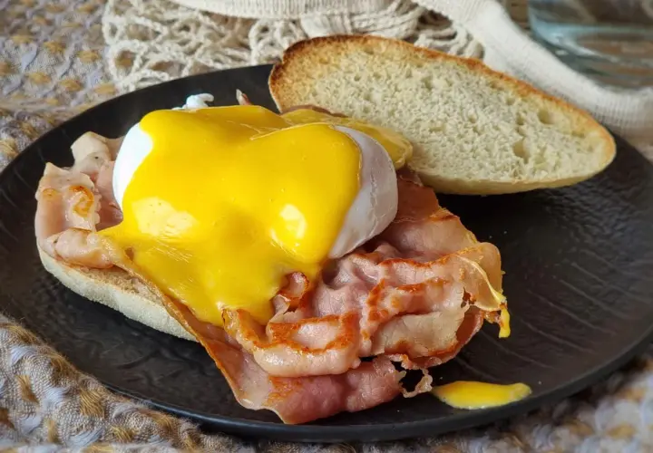 Deliciosos huevos benedictinos con jamón, huevo escalfado y salsa holandesa sobre pan tostado. Un clásico desayuno.