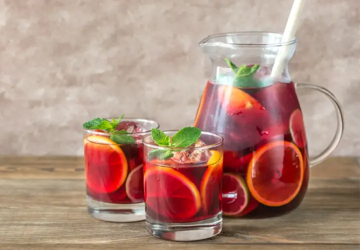Domowa sangria z owocami i winem czerwonym: orzeźwiający napój w dzbanku i szklankach, ozdobiony plasterkami cytrusów i miętą.