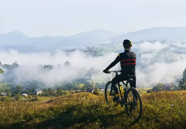 Rowerzysta podziwia mglisty krajobraz Dolnego Śląska. Widok na dolinę i góry.