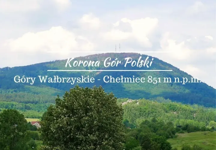 Widok na górzysty krajobraz z dominującym szczytem Chełmiec. Na pierwszym planie bujna zieleń drzew, w oddali łagodne zbocza górskie pokryte lasem.