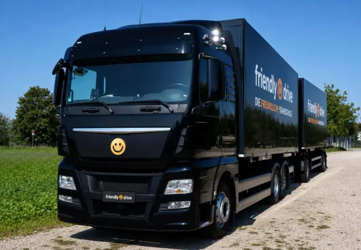 Schwarzer Lkw mit Anhänger, Werbung für "friendly drive - Die freundliche Fahrschule". Ein Smiley-Logo ziert die Front.