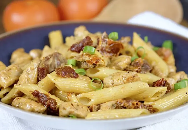 Penne z kurczakiem i suszonymi pomidorami, posypane szczypiorkiem. Pyszne danie, które zachwyci każdego smakosza.