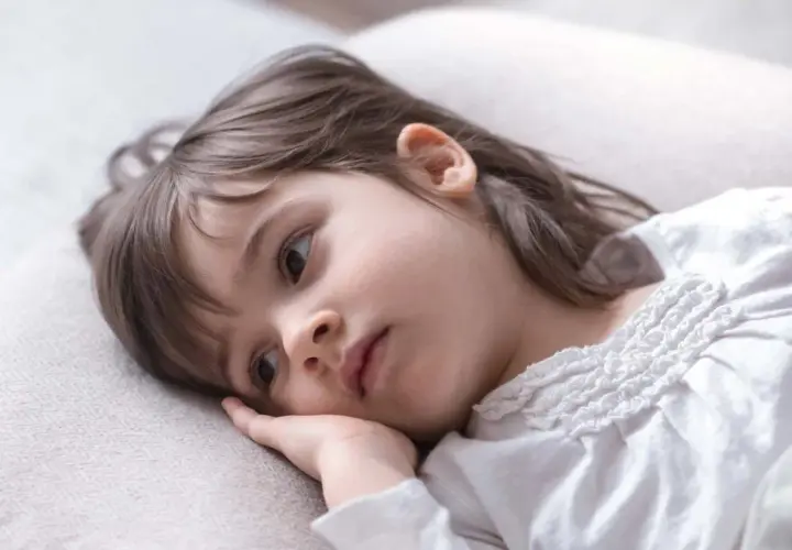 Smutna dziewczynka, 1,5 roczne dziecko, leży na poduszce, nie chce spać, zamyślona.