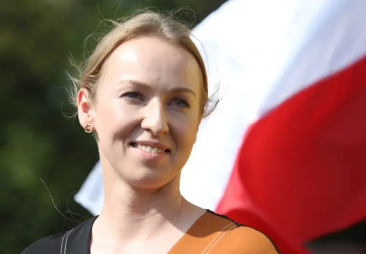 Uśmiechnięta żona Hołowni, niczym pilotka, patrzy w dal na tle biało-czerwonej flagi.