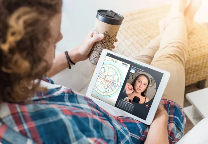 Mężczyzna ogląda na tablecie horoskop, gdzie widoczna jest Wenus w Byku. Kobieta tłumaczy astrologiczne niuanse.