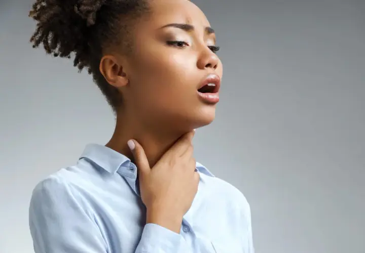 Femme portant la main à sa gorge, bouche ouverte, possiblement atteinte de scarlatine adulte.