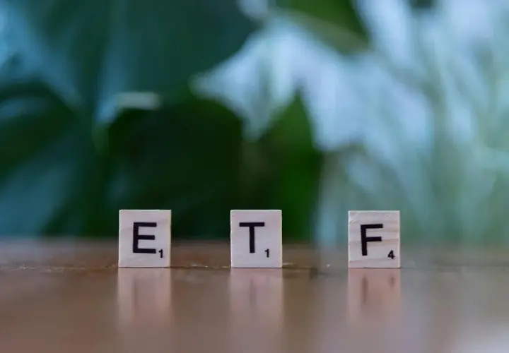 Litery ETF na drewnianych klockach symbolizują inwestycje, które mogą pomóc w nauce, jak zarabiać na giełdzie.