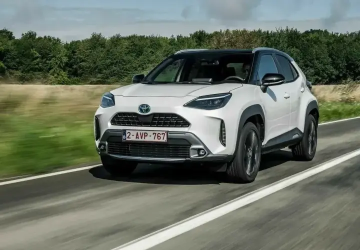 Biały Toyota Yaris Cross 2006 na drodze, z zielonymi drzewami w tle.