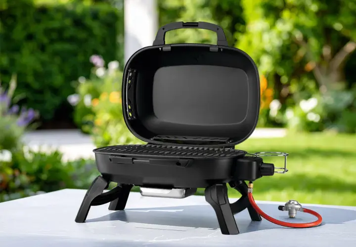 Barbecue à gaz portable, ouvert, avec couvercle, prêt pour de délicieuses recettes barbecue gaz avec couvercle dans un jardin ensoleillé.