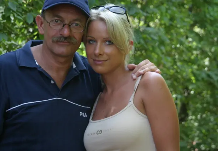 Mężczyzna w okularach i czapce obejmuje kobietę w bluzce na ramiączkach.