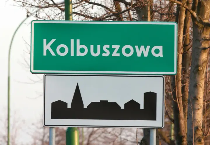 Znak drogowy Kolbuszowa z sylwetką zabudowy miejskiej. Wjazd do miasta.