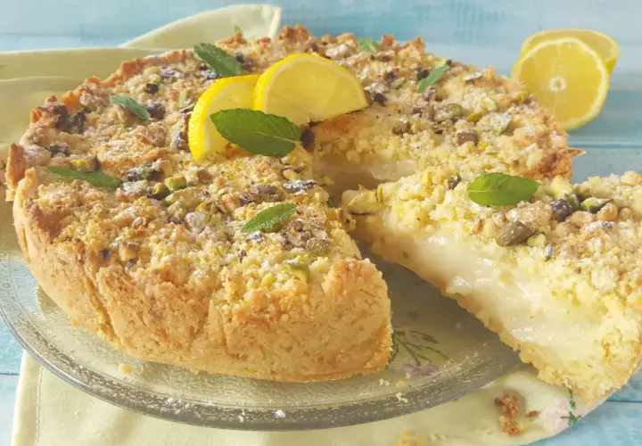 Deliziosa sbriciolata al limone con crema soffice, guarnita con pistacchi, menta e spicchi di limone fresco.
