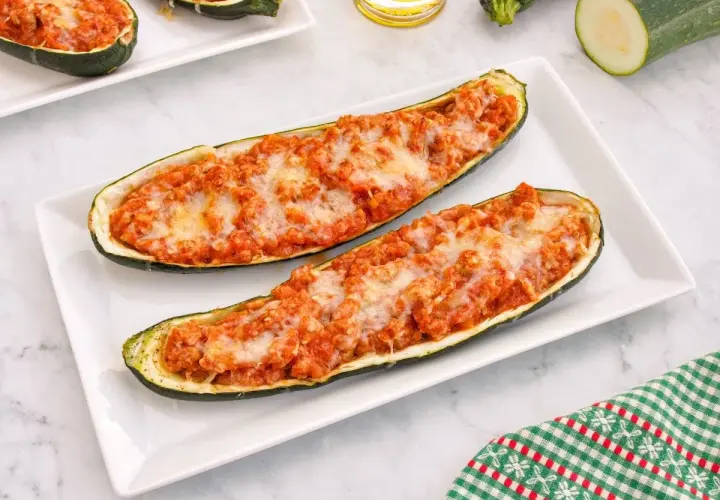 Dos calabacines rellenos de carne y queso gratinado, servidos en un plato blanco.