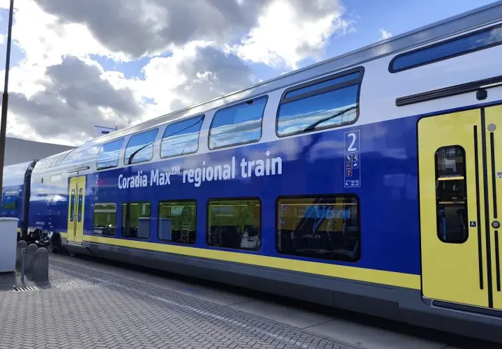 Niebiesko-żółty dwupoziomowy wagon kolejowy Coradia Max™ regional train stoi na peronie.