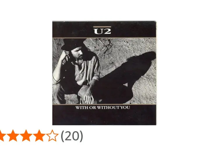 U2 w kadrze z piosenki "With or Without You". Mężczyzna w kapeluszu siedzi na ziemi, rzucając długi cień.