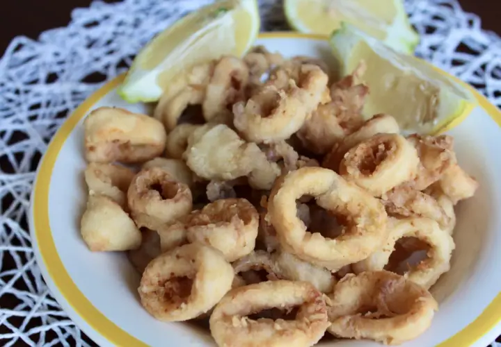Un piatto invitante di frittura di calamari dorati e croccanti, accompagnati da spicchi di limone fresco.