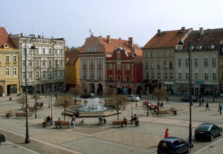 Rynek Wałbrzych tętni życiem. Ludzie odpoczywają przy fontannie, spacerują między kamienicami.