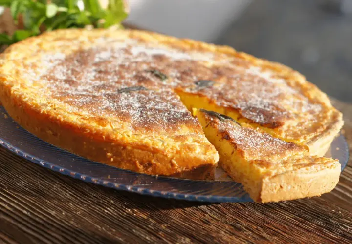 Tarta dorada con azúcar glas, un trozo cortado, como un flao ibiza.