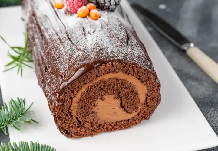 Bûche de Noël au chocolat, parfaite pour une recette génoise bûche moelleuse. Garnie de fruits rouges et de sucre glace.