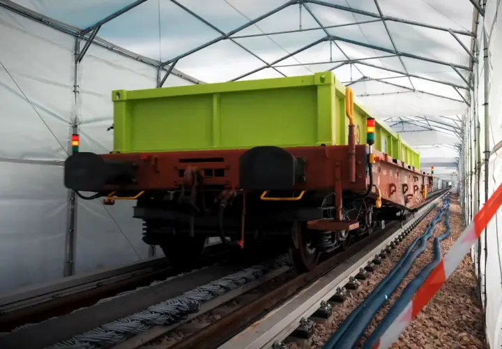 Zielony wagon towarowy na torach pod namiotem. Może to być pierwsza kolej na świecie w takim wydaniu.