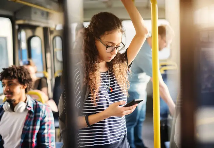 Ragazza sul bus guarda il suo telefono, forse controllando l'orario della metro linea A di Roma per il suo prossimo viaggio.