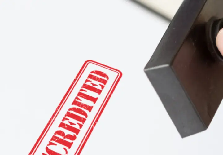 A hand presses a stamp, leaving a red "ACCREDITED" mark. This signifies official MPA accreditation.
