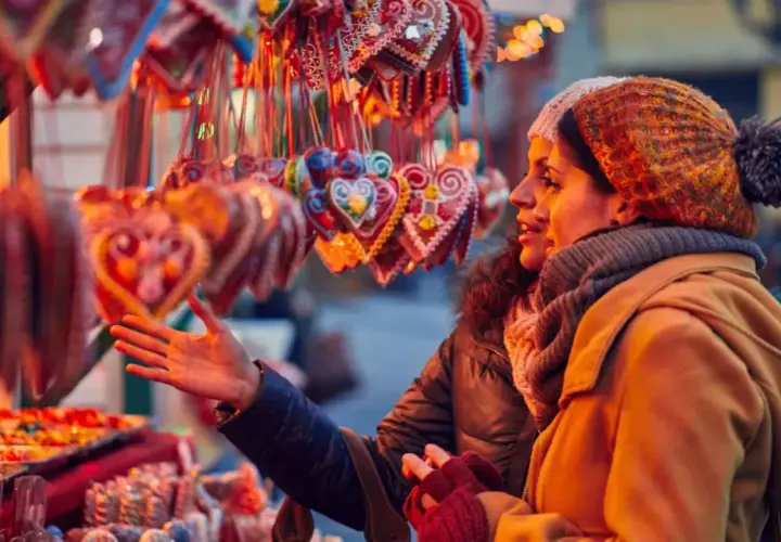 Dos mujeres admiran dulces y galletas en forma de corazón en un mercadillo de Santillana del Mar.