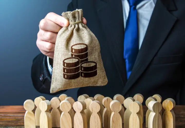 Hr manager w garniturze trzyma worek z pieniędzmi nad grupą drewnianych ludzików.