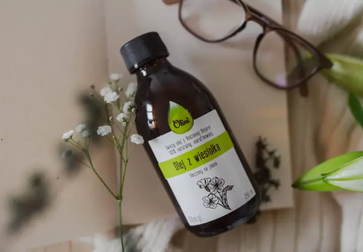 Butelka z naturalnym olejem z wiesiołka, idealnym do pielęgnacji włosów. Delikatne kwiaty podkreślają jego naturalne pochodzenie.