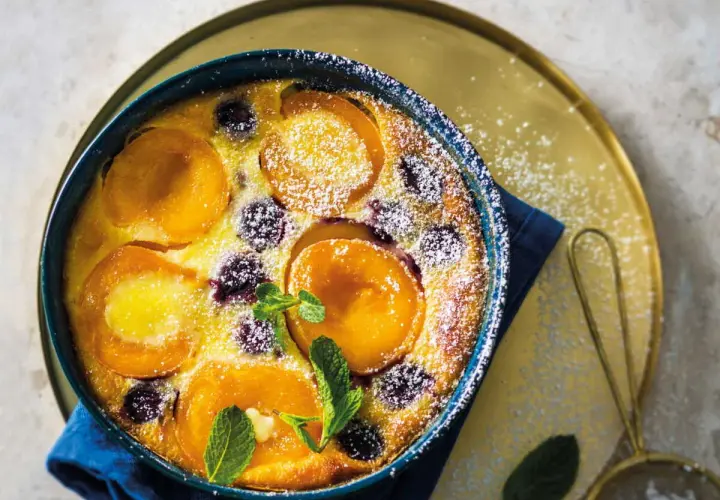Un délicieux clafoutis abricot, saupoudré de sucre glace et garni de feuilles de menthe fraîche.