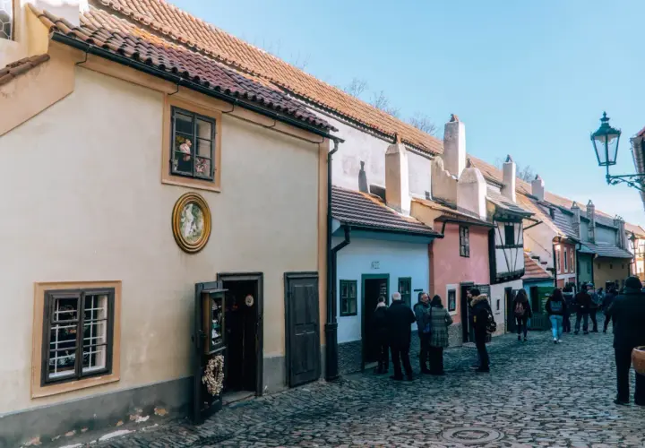 Uliczka Złota w Pradze, z kolorowymi domkami i brukowaną ścieżką, przyciąga turystów.