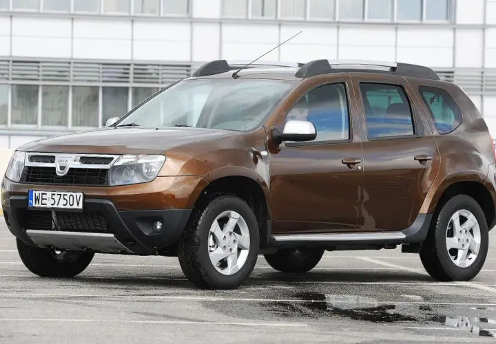 Brązowy Dacia Duster na parkingu. Zastanawiasz się, dacia duster jaki silnik wybrać? Ten model ma napęd 4x4.