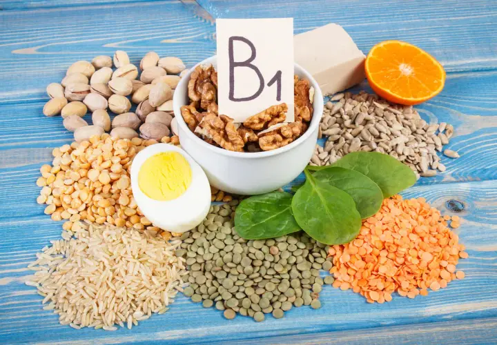 Vielfalt an vitamin b1 lebensmittel: Nüsse, Linsen, Reis, Erbsen, Ei, Spinat, Sonnenblumenkerne, Orange und Hefe.