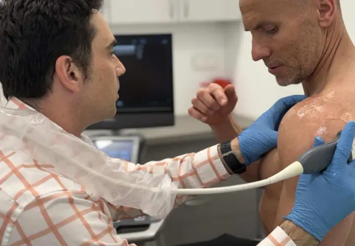 Lekarz wykonuje USG barku pacjenta, diagnozując entezopatię barku.