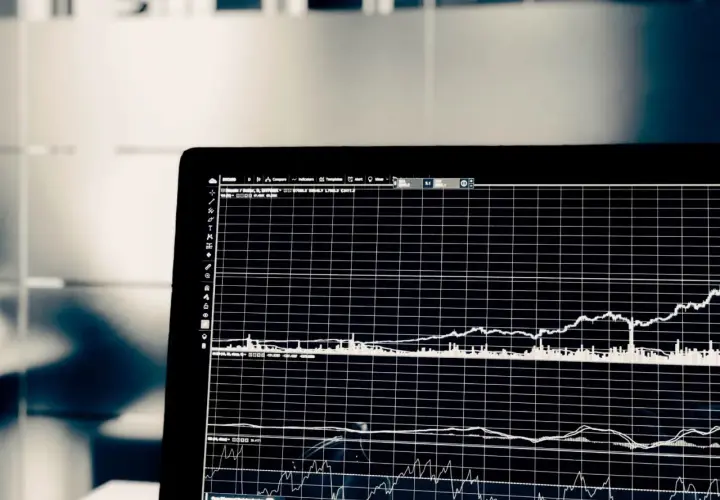 Wykresy na ekranie laptopa pokazują zmienność cen akcji. Analiza tych danych pomaga w ocenie, co to jest scoring finansowy i jak podejmować trafne decyzje inwestycyjne.