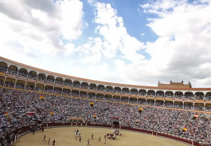 Gran multitud asiste a una corrida de toros. El sol brilla en el cielo azul con nubes blancas. ¡Una visita a la plaza de toros es una experiencia inolvidable!