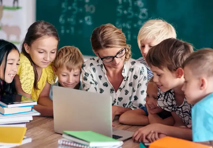 Nauczycielka z uczniami przy laptopie. Szukają informacji, gdzie znaleźć sprawdziany z nowej ery.