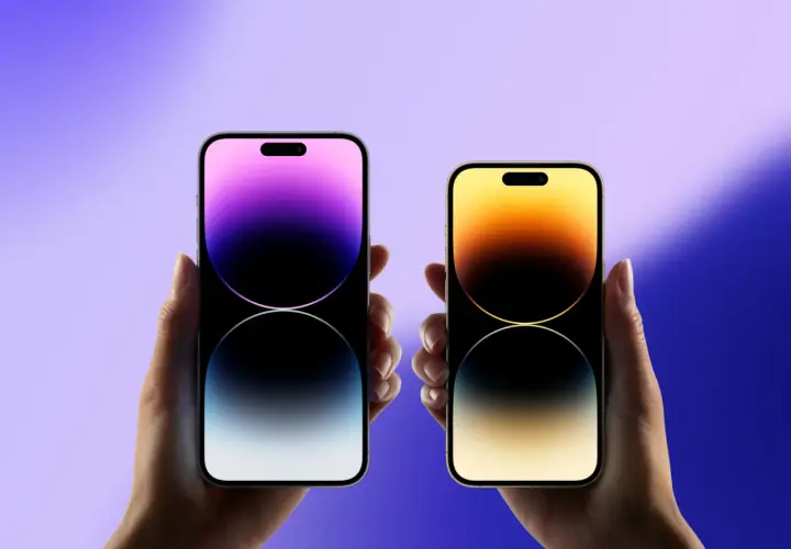 Dwie dłonie trzymają iPhone'y, gdy wyszedł iPhone 15. Jeden z fioletowym gradientem, drugi z żółto-pomarańczowym.