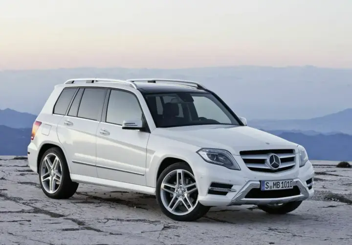Weißer Mercedes GLK steht auf felsigem Untergrund vor bergiger Kulisse.