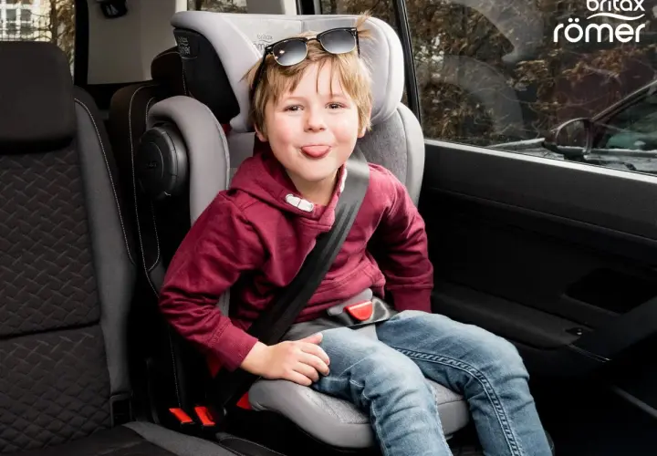 Chłopiec w foteliku samochodowym Britax Römer, z językiem na wierzchu, w okularach przeciwsłonecznych na głowie. Jaki fotelik samochodowy wybrać?