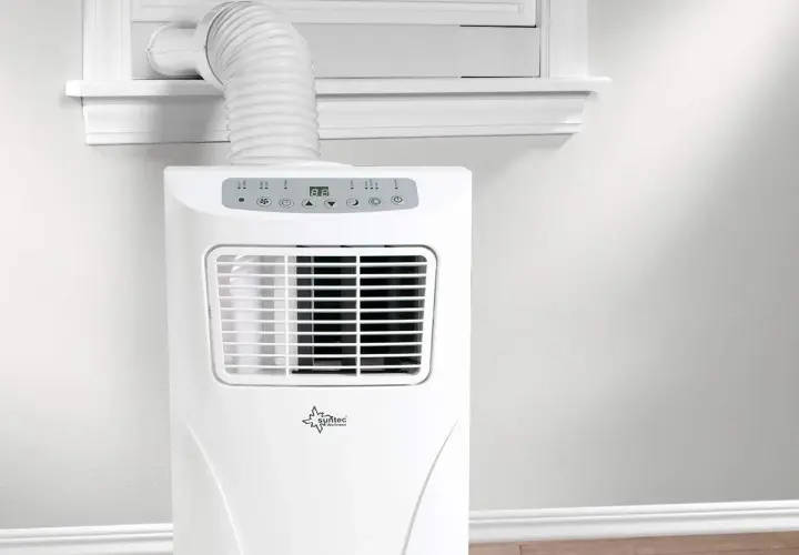 Un aire acondicionado portátil con un tubo para sacar aire caliente por la ventana.