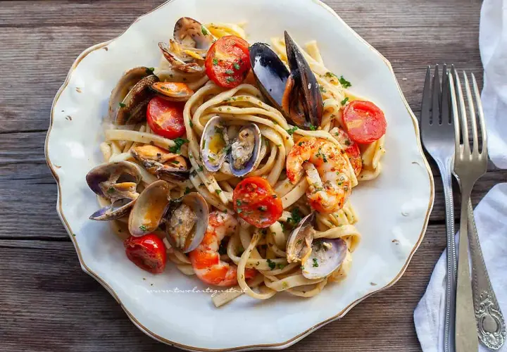 Un piatto invitante di scialatielli ai frutti di mare, con cozze, vongole, gamberi e pomodorini freschi, guarnito con prezzemolo.