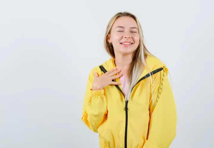 Uśmiechnięta blondynka w żółtej kurtce softshell. Dowiedz się, jak prać softshell, by zachować jego właściwości.